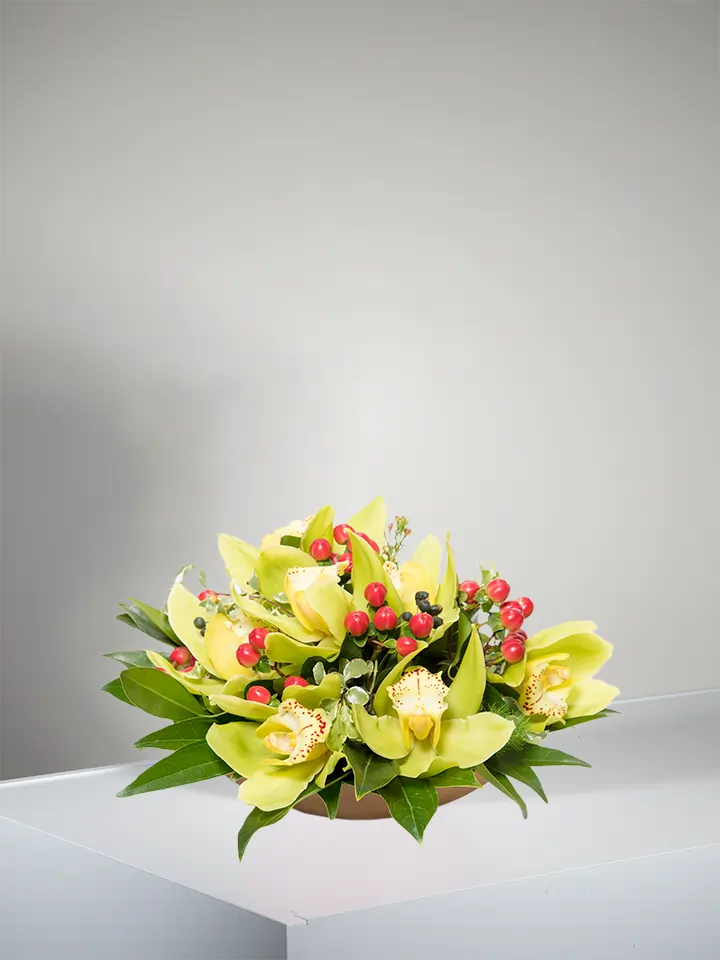 Centrotavola di fiori di cymbidium gialli e bacche rosse